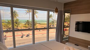 A hotel room with a large window offering a view of palm trees and a road with motorcycles.