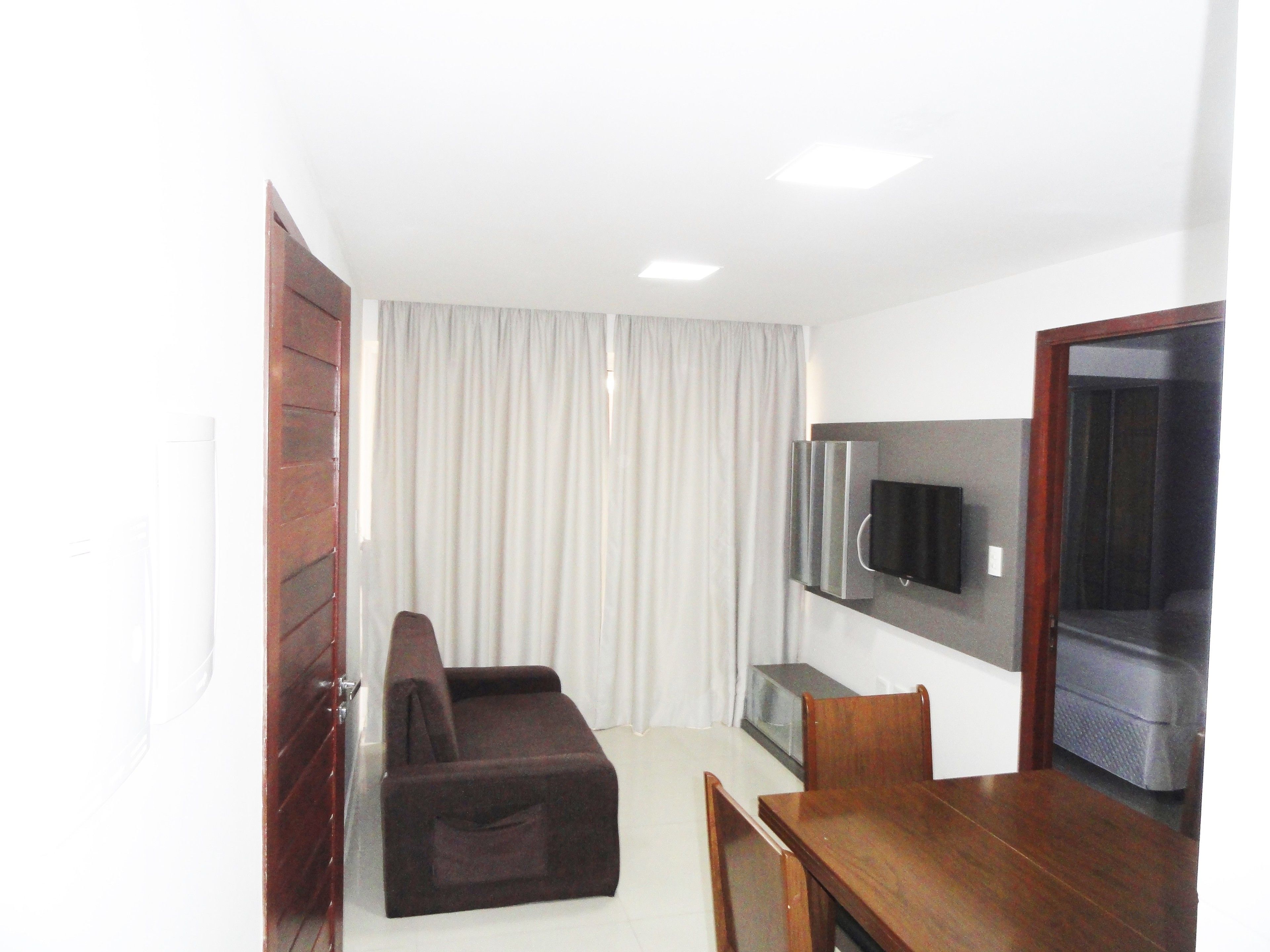Un espacio habitable compacto con sofá, mesa de comedor y televisor de pantalla plana montado en la pared.