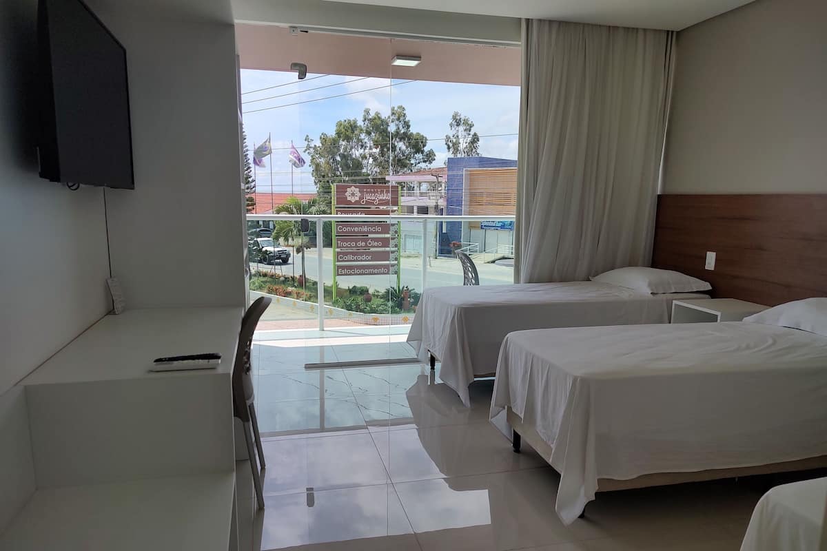 A hotel room with two beds, a desk, and a TV.