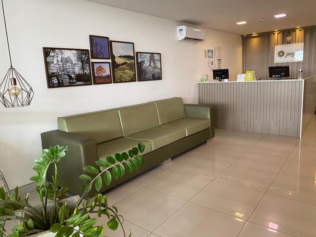 Een receptiegedeelte met een groene bank, een receptiebalie en ingelijste foto’s aan de muur.
