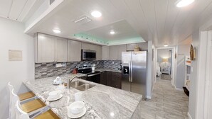 A modern kitchen with granite countertops, stainless steel appliances, and a large island with seating.