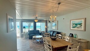 A spacious dining area with a wooden table and chairs, a blue sofa, and a chandelier.