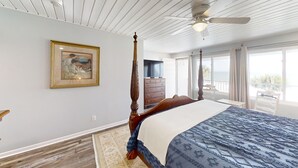 A spacious bedroom with a large bed, a ceiling fan, a wooden dresser, and a painting on the wall.