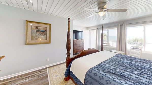 Ein geräumiges Schlafzimmer mit einem großen Bett, einem Deckenventilator, einer hölzernen Kommode und einem Gemälde an der Wand.