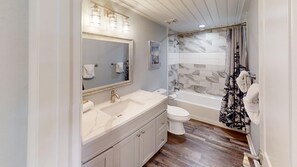 Ein Badezimmer mit Marmorwaschbecken, Toilette, Badewanne und Duschvorhang.