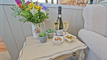 Una mesa con un jarrón de flores, una botella de champán, dos copas y recipientes pequeños con aperitivos.