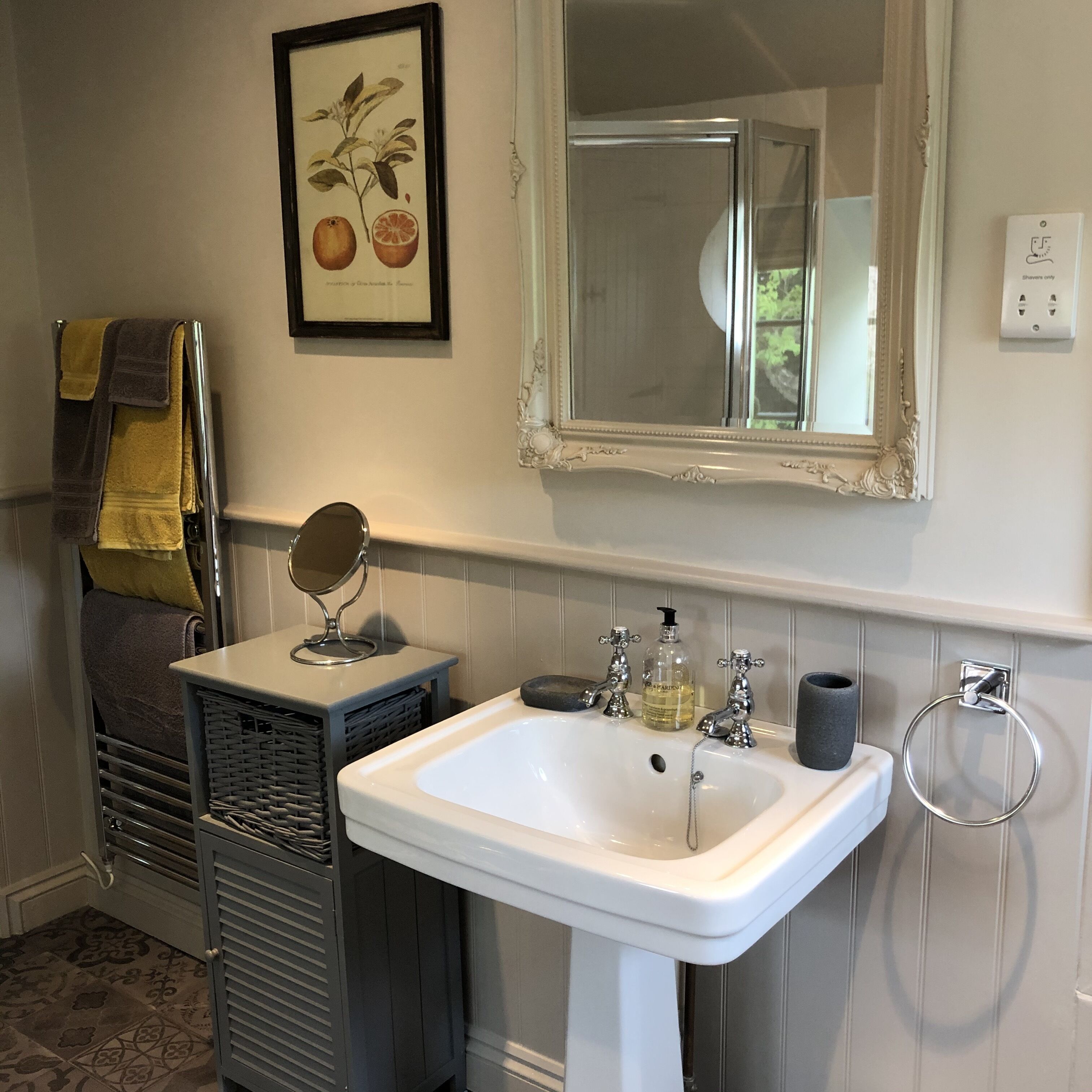 A bathroom with a white sink, a mirror, and a framed botanical print on the wall.