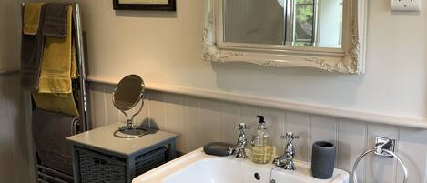 A bathroom with a white sink, a mirror, and a framed botanical print on the wall.