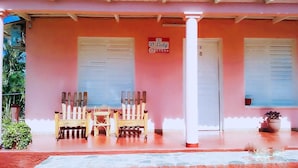 Un edificio de fachada rosa, dos sillas de madera, una mesa pequeña y un letrero que dice 