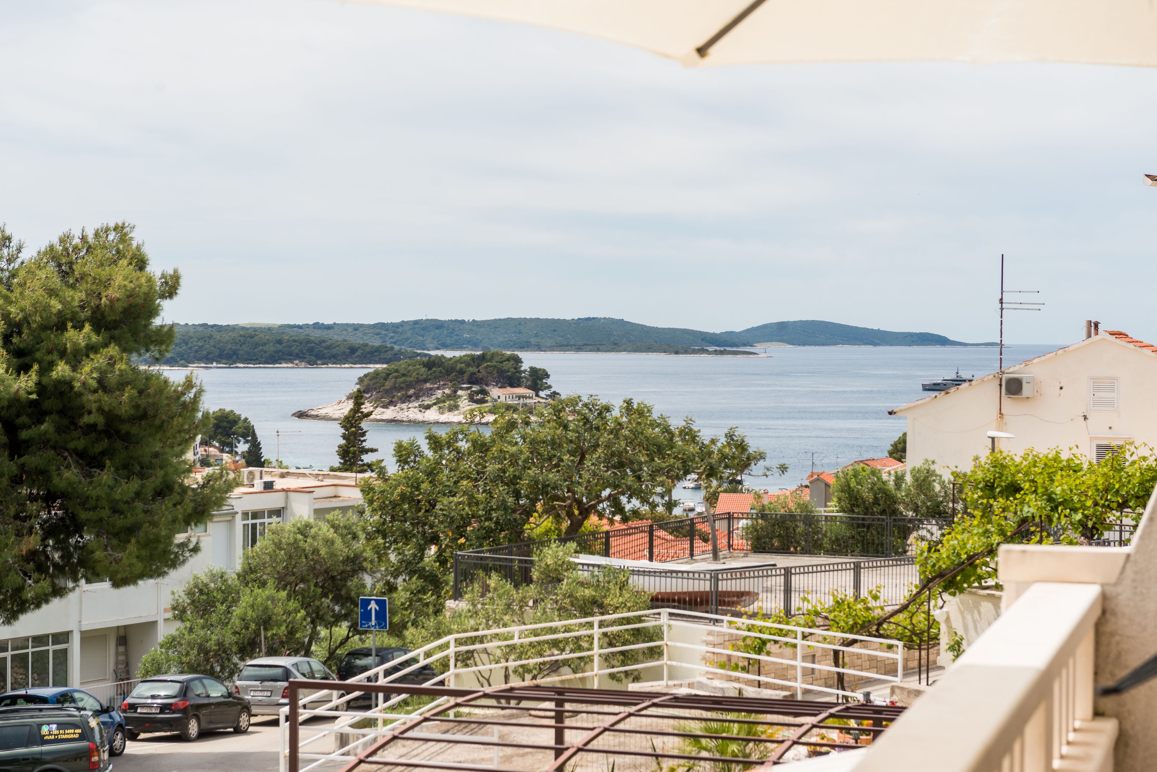 A coastal view with a clear sky, a small island, and a building with a balcony overlooking the sea.