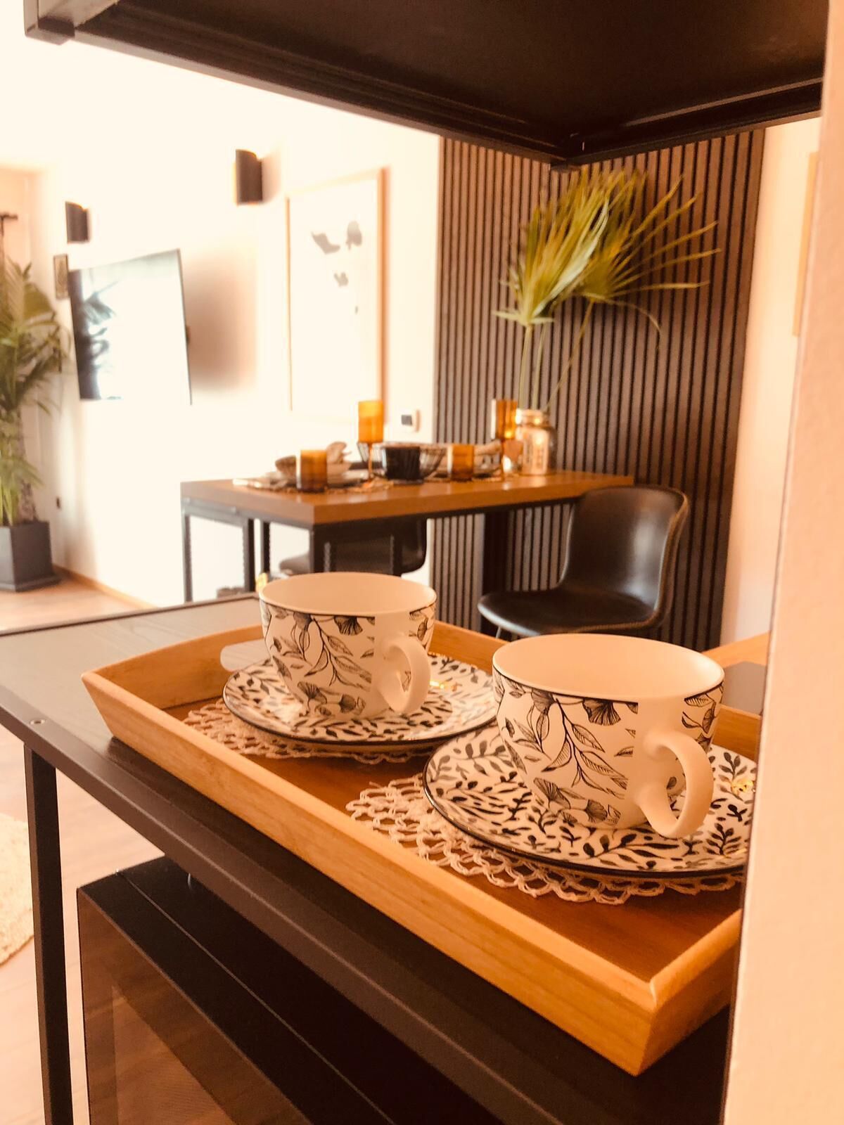 Una bandeja con dos tazas y platitos de estampado floral sobre una mesa de madera.