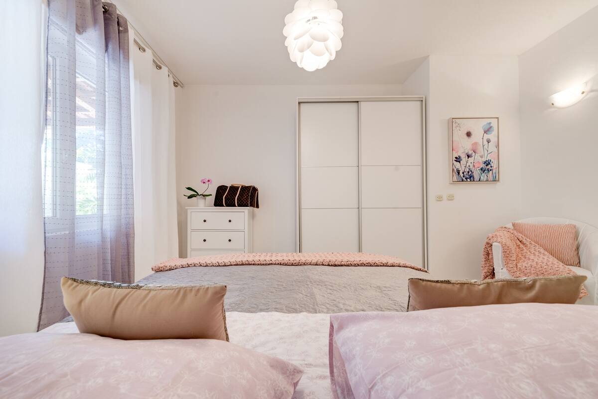 A bedroom with a bed, two bedside tables, a wardrobe, and a painting on the wall.
