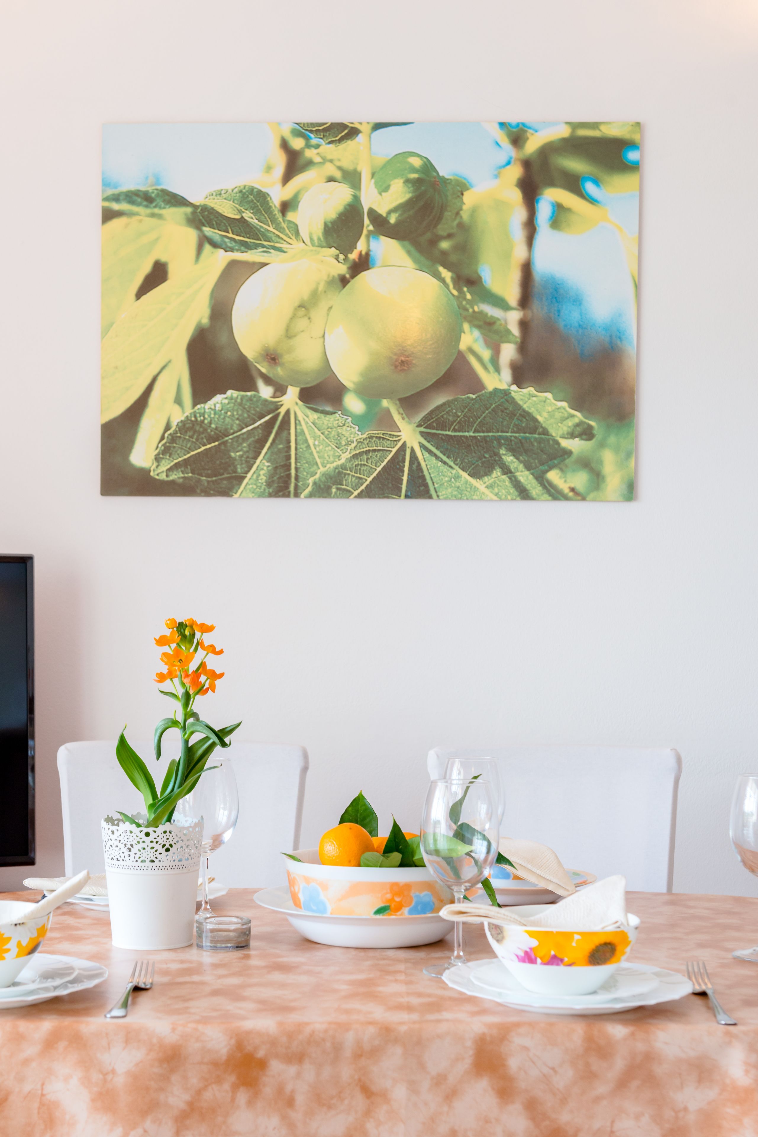 A dining table set with plates, bowls, and a vase of flowers.
