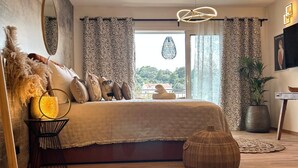 Un dormitorio moderno con una cama grande, una lámpara colgante y vistas al exterior.