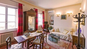 A cozy living room with a dining table, sofa, and a large mirror. - Santo Agostino Belvedere - Apartment in Cortona (Cortona)
