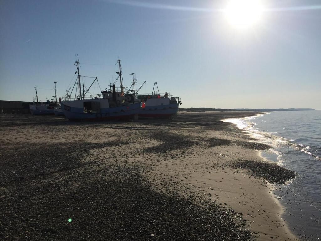 Une plage avec des bateaux amarrés et un soleil éclatant.