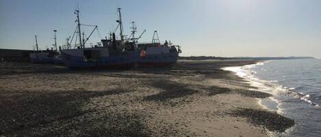 Une plage avec des bateaux amarrés et un soleil éclatant.