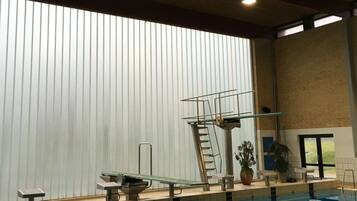An indoor swimming pool with diving platforms and a ladder.