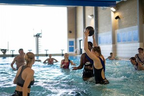 An indoor swimming pool with people engaged in water activities.