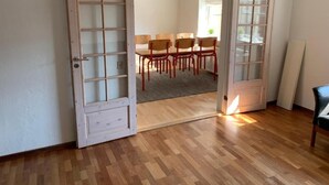 Une pièce dotée d’un plancher en bois, d’une table à manger avec des chaises et d’une porte donnant sur une autre pièce.