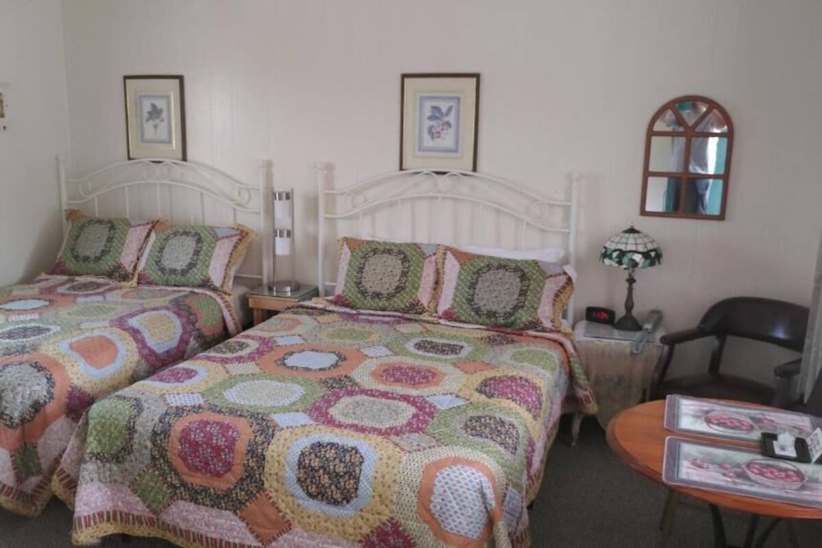 A room with two beds, a small table, and a chair.