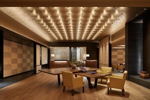 A modern conference room with a wooden table, leather chairs, and recessed lighting on the ceiling.