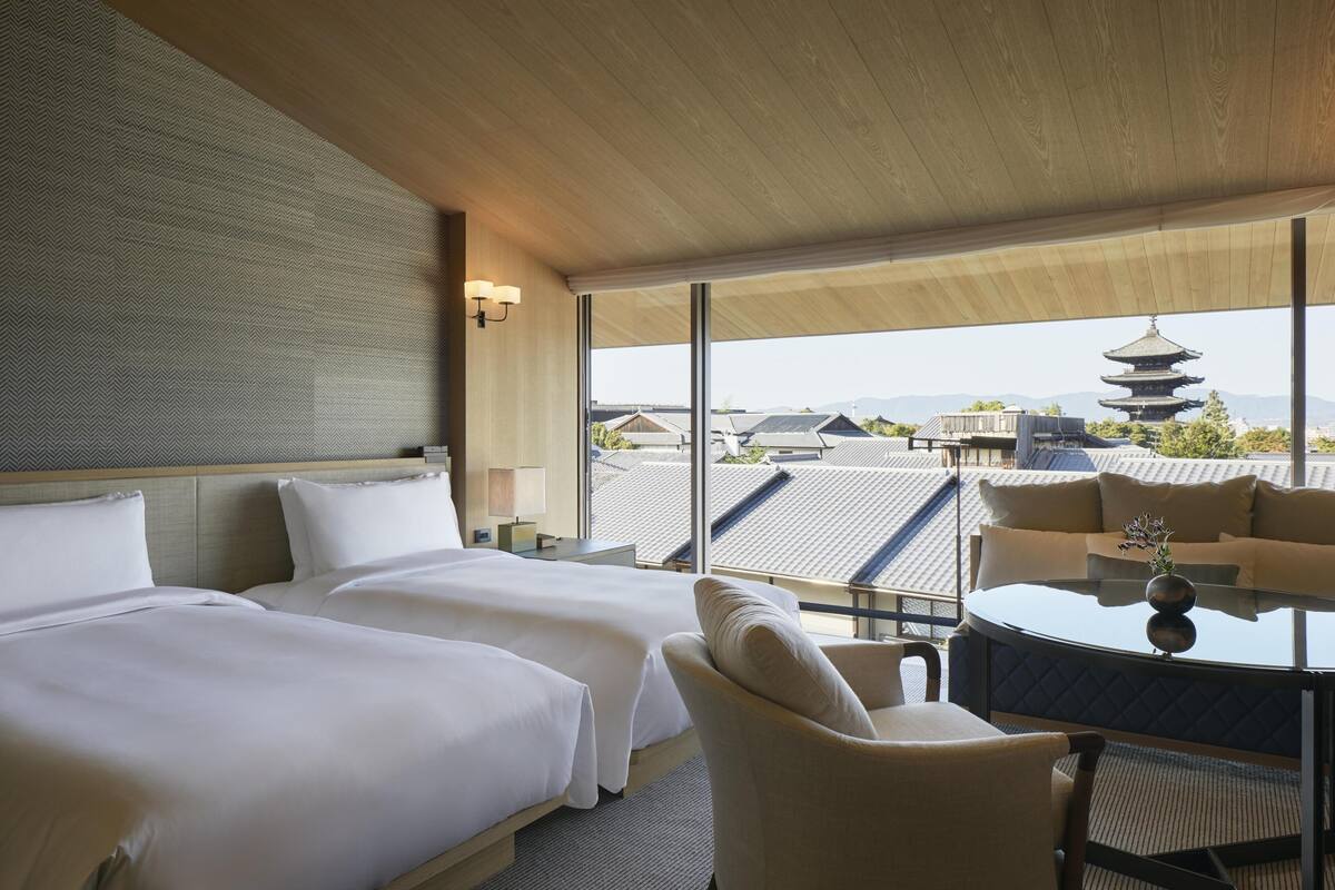 Ein Hotelzimmer mit zwei Betten, einem runden Tisch und Blick auf traditionelle Pagoden.