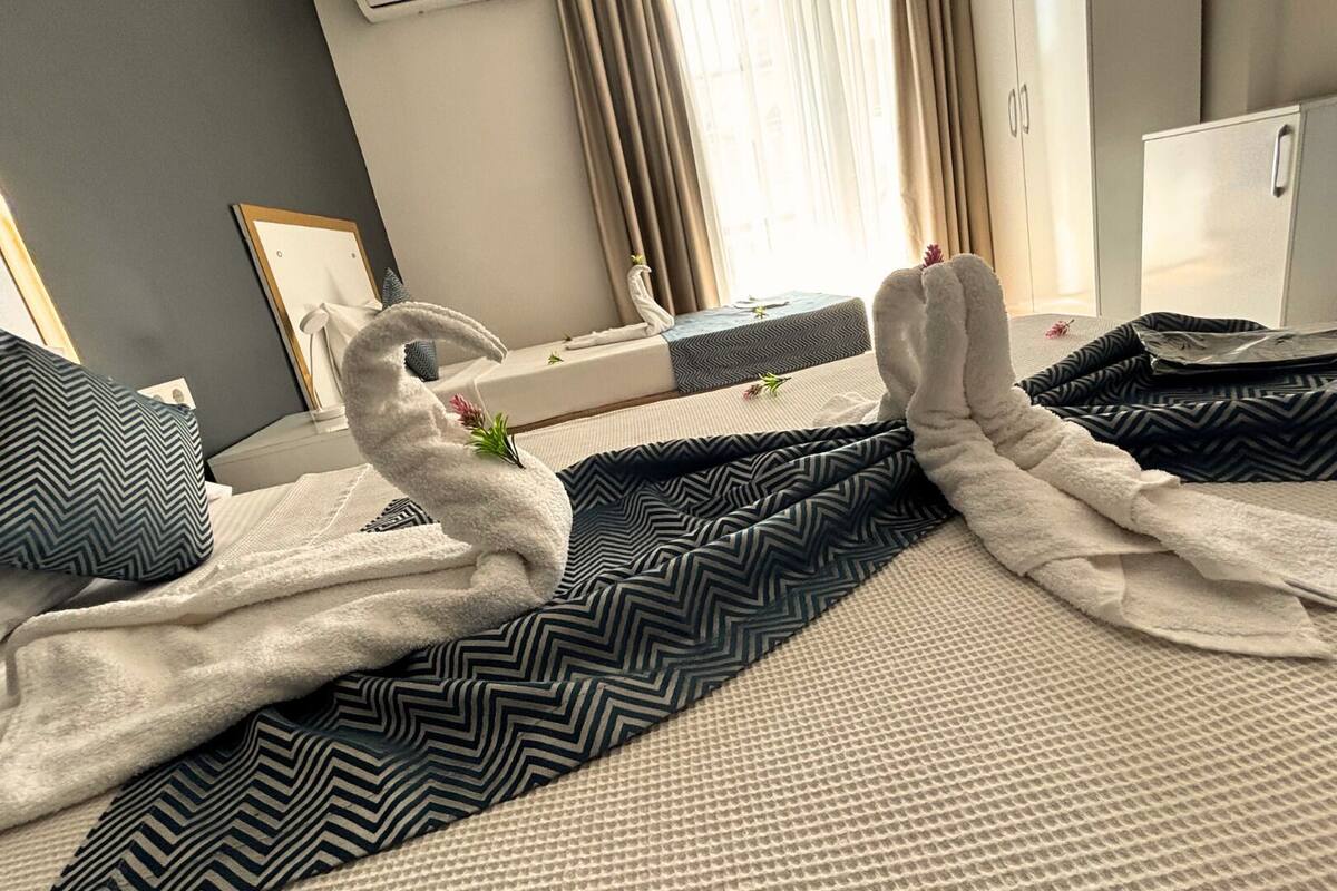 A hotel room with a bed, pillows, and a towel rack.