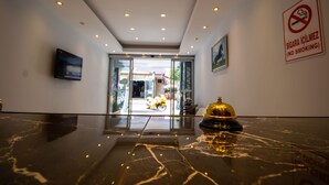 A hotel lobby with a marble floor, a reception desk with a bell, and a no-smoking sign. - Moonbow Beach Hotel (Alanya)