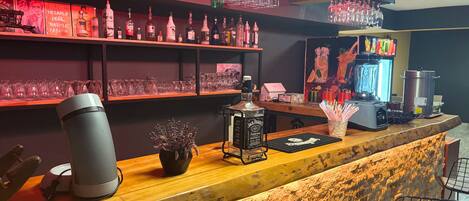 A bar area with shelves of liquor bottles, a Jack Daniel's bottle, a blender, and a coffee machine.