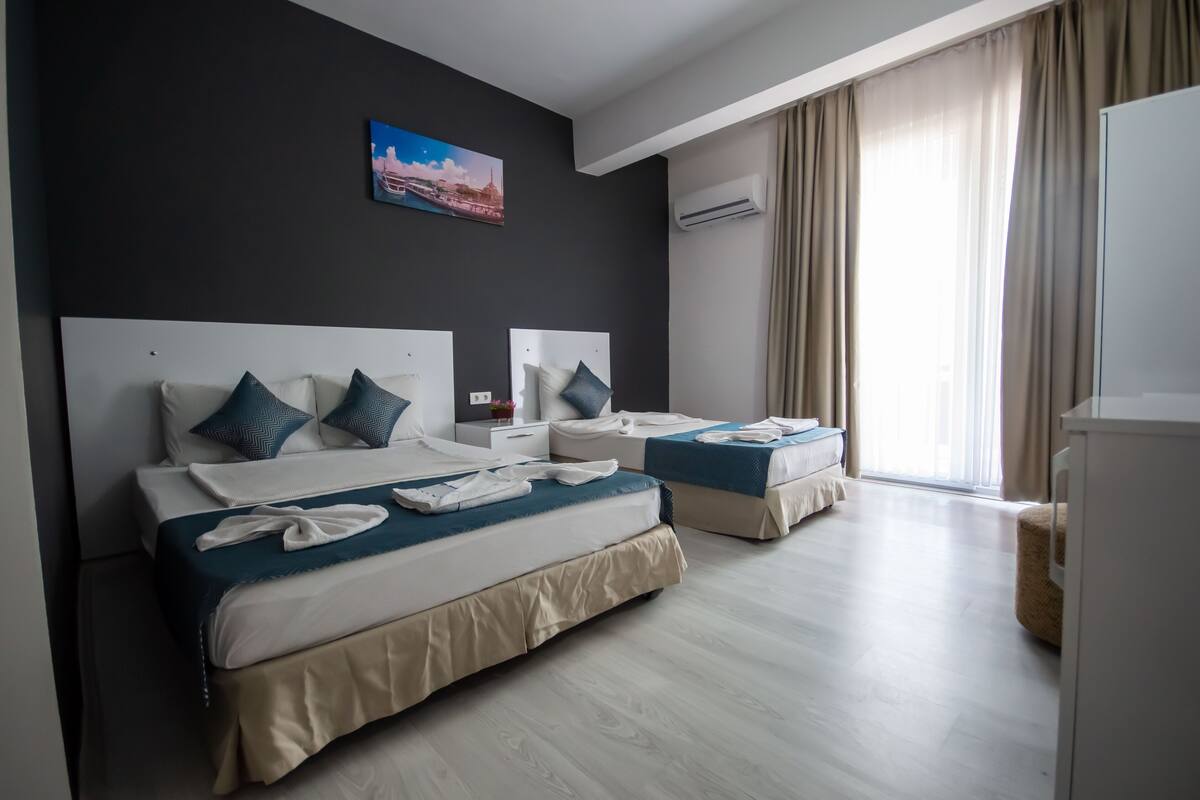A hotel room with two beds, a painting on the wall, and an air conditioning unit.
