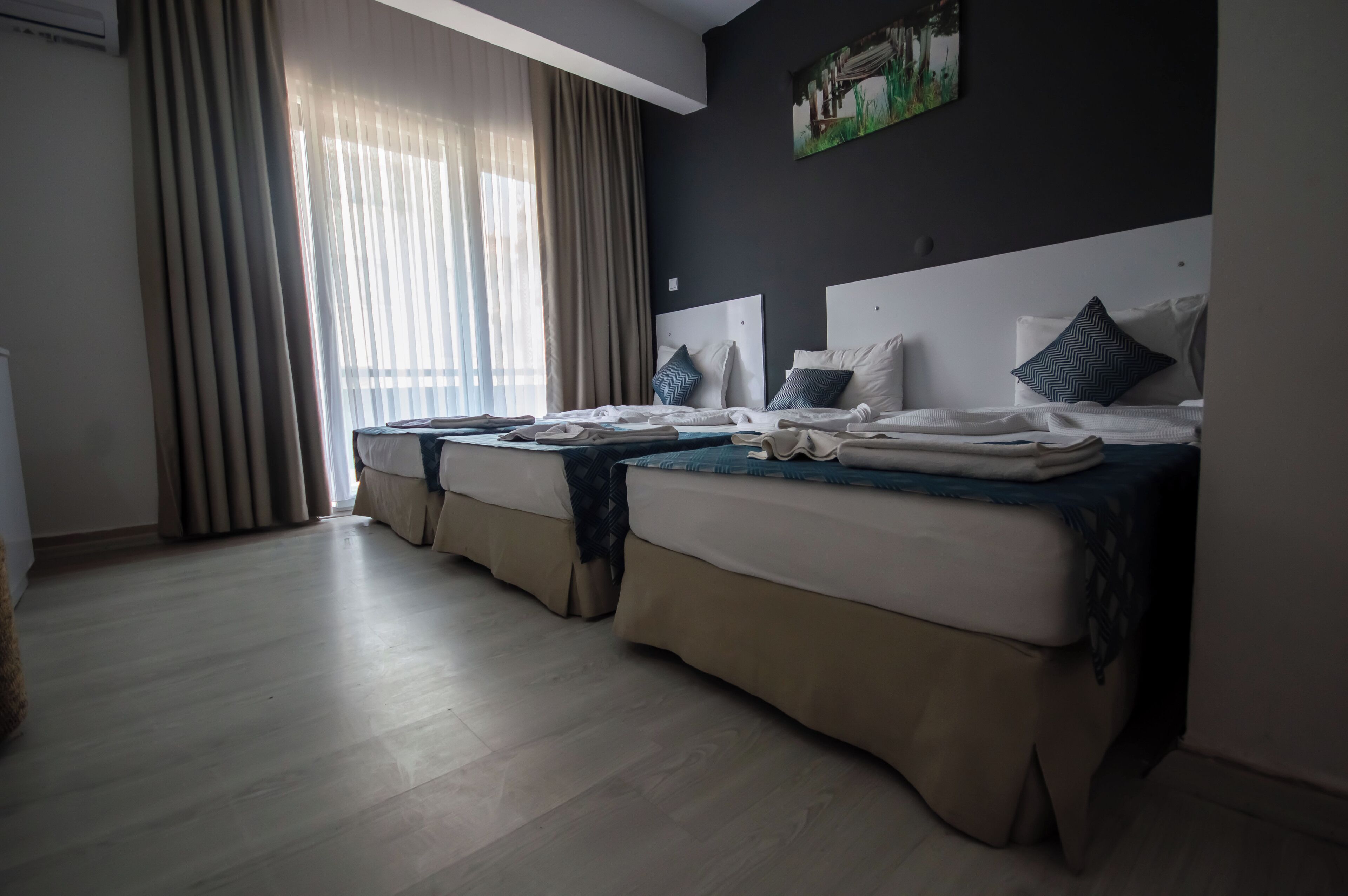 Una habitación de hotel con dos camas, un ventanal con cortinas y un cuadro en la pared.