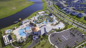 An aerial view of a resort with multiple swimming pools, a parking area, and a large body of water. - Storey Lake 4820 (Kissimmee)