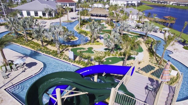 A water park with a large green water slide, multiple pools, and palm trees. - Storey Lake 4820 (Kissimmee)