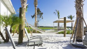 A beach area with a hammock, lounge chairs, and a wooden structure. - Storey Lake 4820 (Kissimmee)