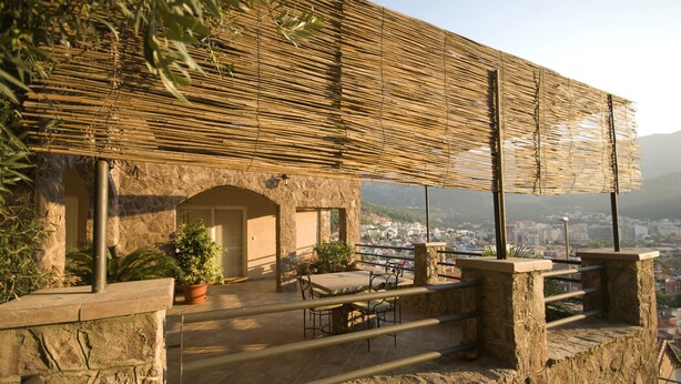 Une terrasse extérieure avec des murs en pierre, un toit en bambou et une vue sur le paysage urbain.