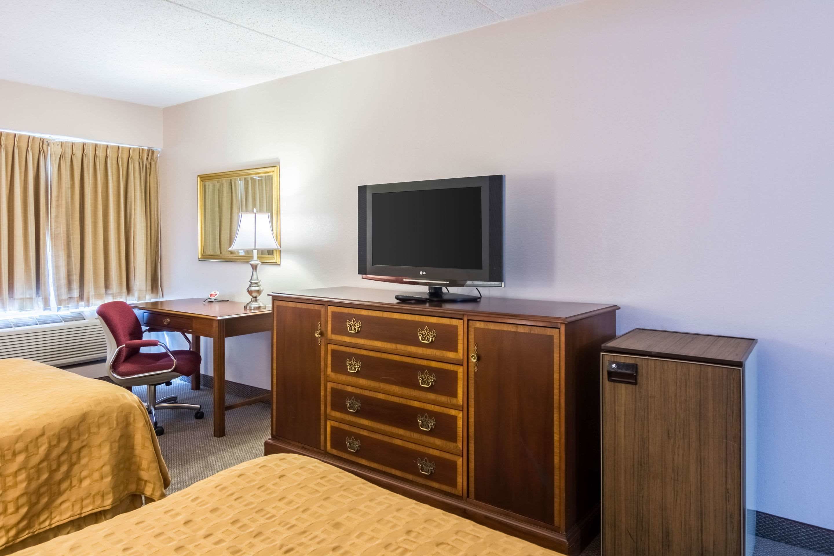 Une chambre d’hôtel comprenant un lit, un bureau, une télévision, une armoire et une chaise.