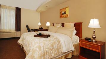 A hotel room with a large bed, two bedside lamps, a nightstand with a lamp, a chair, a desk, and a painting on the wall.