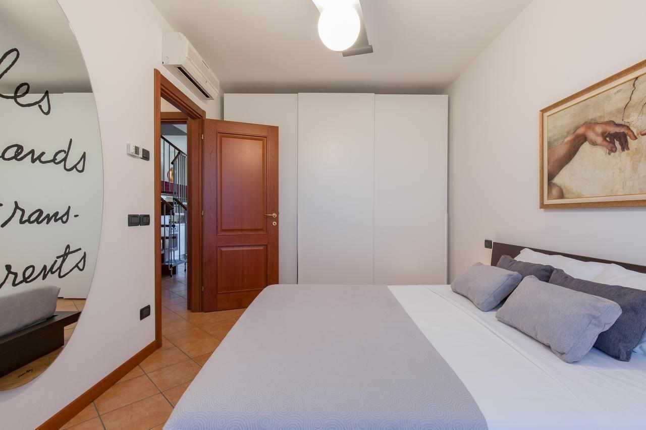 Une chambre à coucher avec un lit, des oreillers, un tableau et une porte donnant sur un couloir.