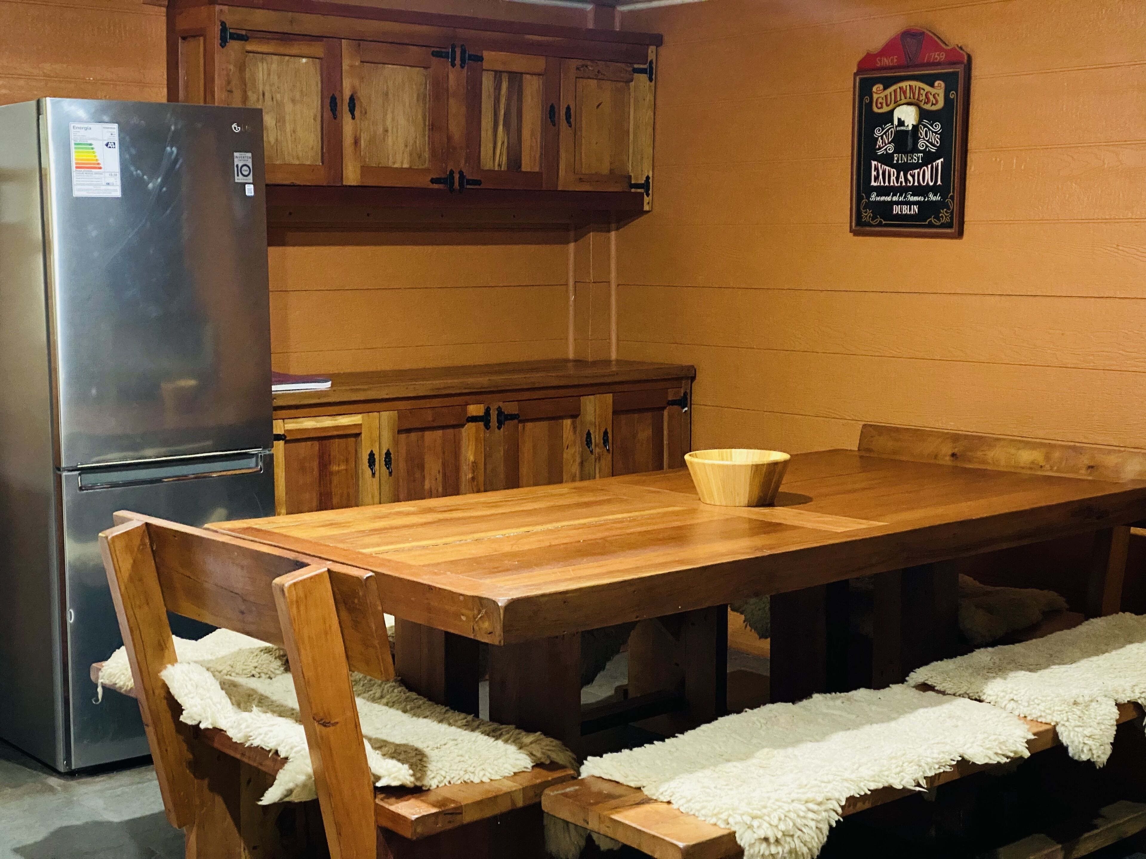 A kitchen with wooden cabinets, a stainless steel refrigerator, and a wooden dining table with chairs.