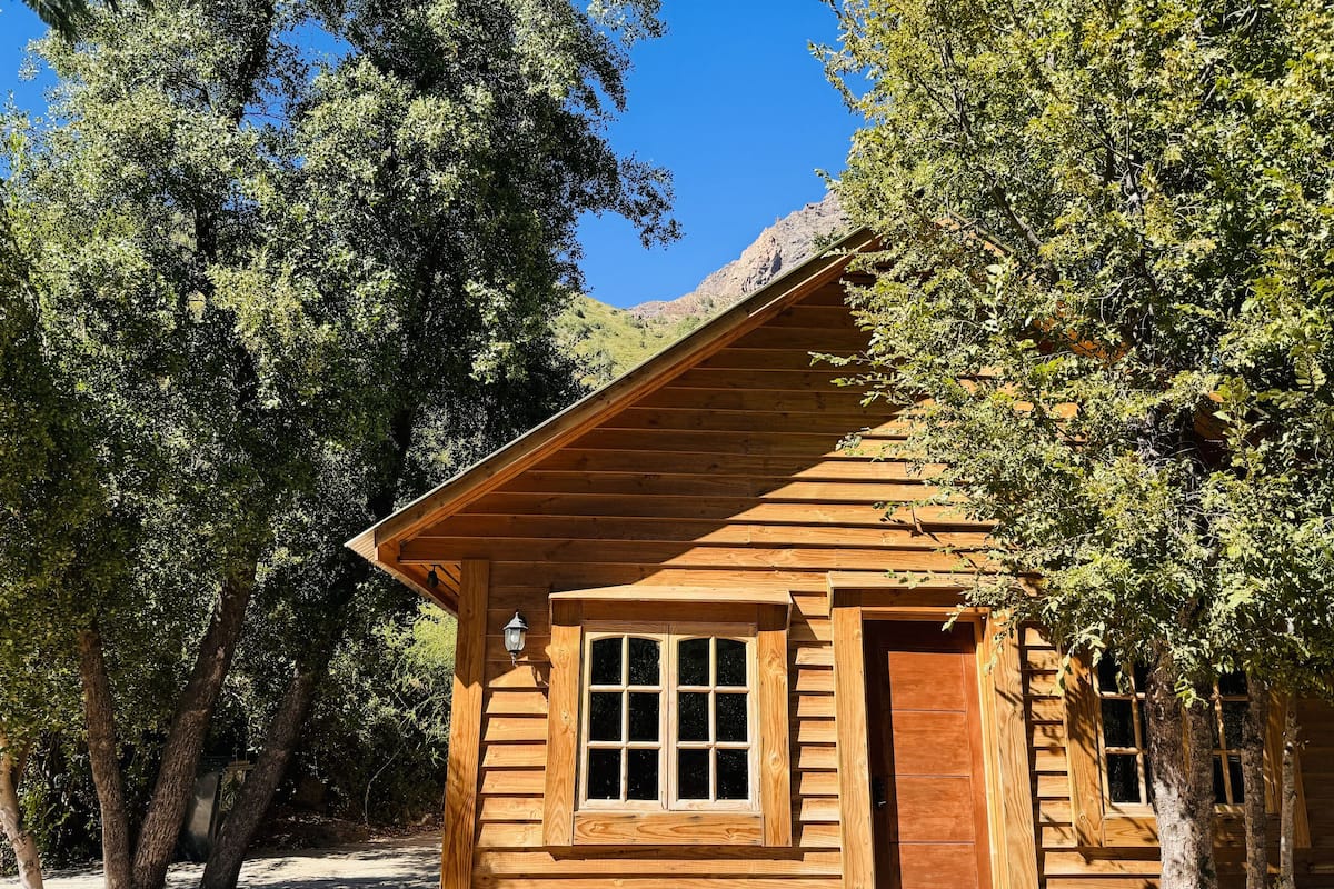 Une cabane en bois avec une porte d’entrée, une fenêtre et une véranda.