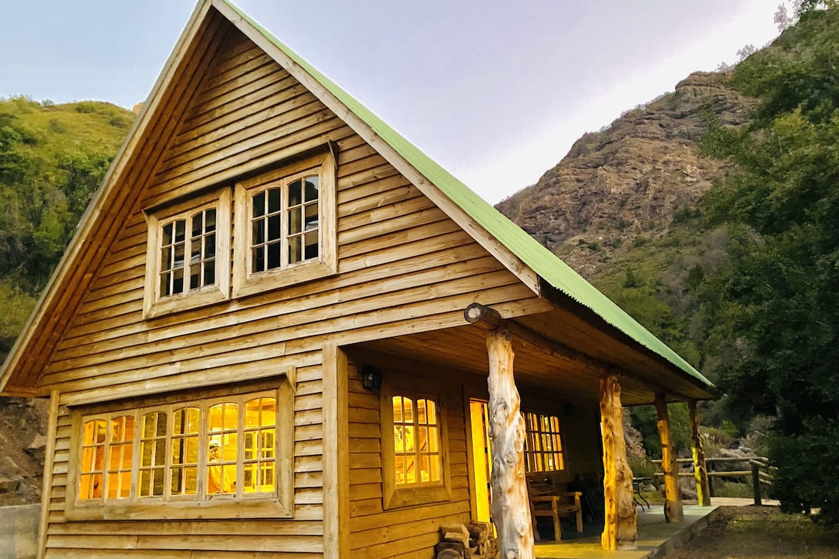 Une cabane en bois avec un toit à pignon, de grandes fenêtres et une véranda.