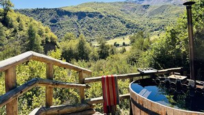 A wooden deck with a hot tub overlooking a mountainous landscape.
