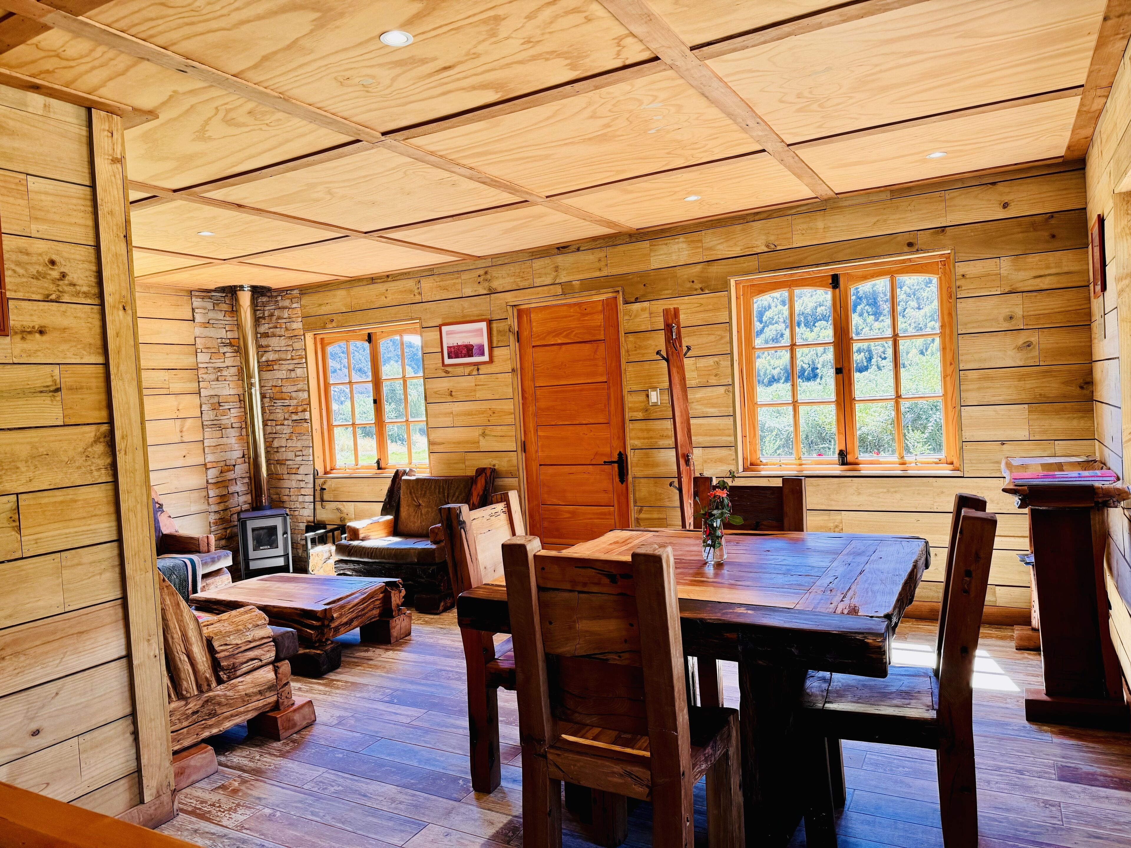Un interior rústico de madera con una mesa de comedor, sillas y una chimenea.