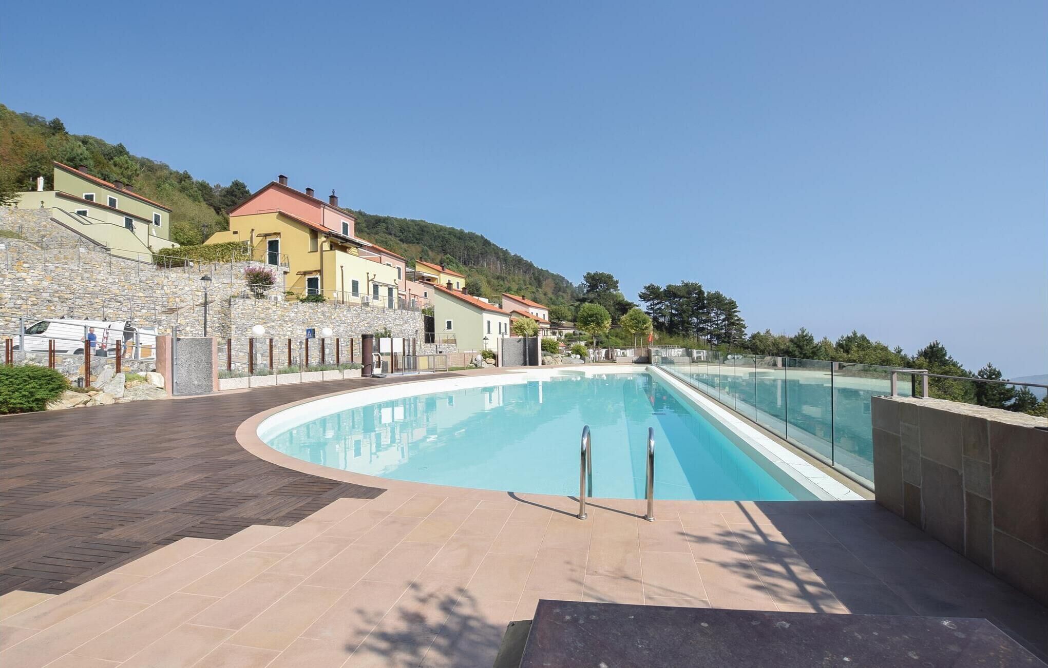 Une piscine à bord incurvé, entourée d’un mur de pierre et d’une terrasse en bois.