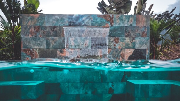 Una piscina amb cascada i mur de pedra.