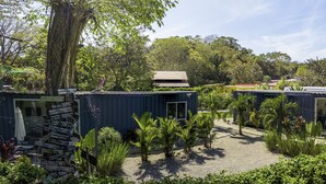 Un pati amb habitatges modulars, envoltat de vegetació i arbres frondosos.
