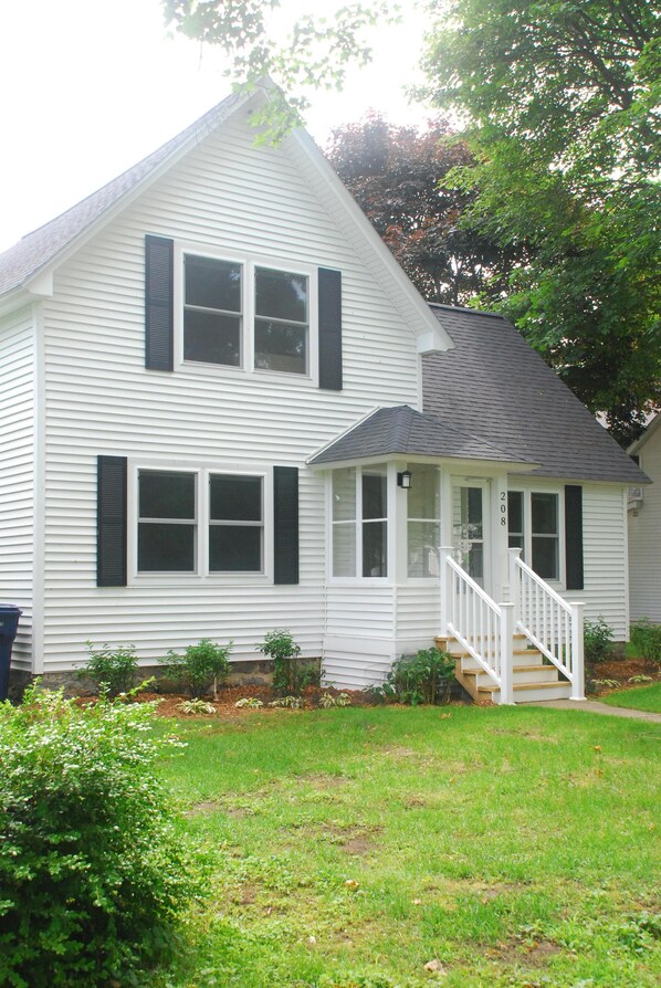 A two-story house with a front porch and a staircase leading to the entrance.