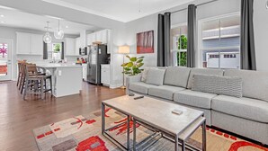 Un appartement moderne comprenant une cuisine, un coin repas et un salon. Il dispose d’une grande fenêtre, d’un ventilateur de plafond et d’un canapé offrant une belle vue.