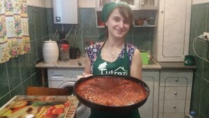 Une cuisine avec une grande casserole remplie de nourriture, un lave-linge et un mur recouvert de carreaux.